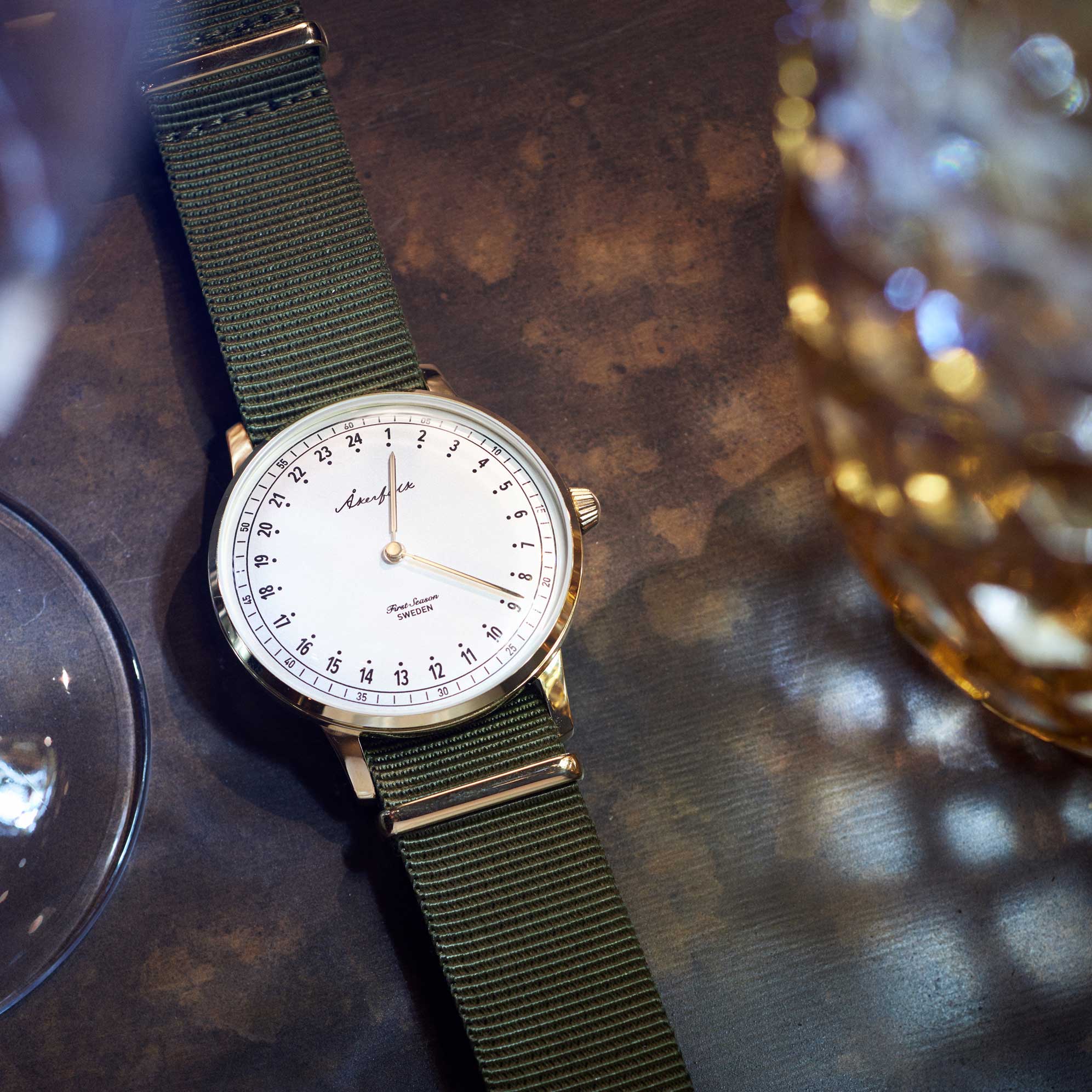 24-hour watch with gold case and green NATO strap